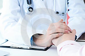 Friendly female doctor hands holding patient hand sitting at the desk for encouragement, empathy, cheering and support