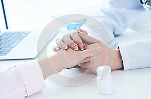 Friendly female doctor hands holding patient hand sitting at the desk for encouragement, empathy, cheering and support