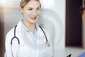 Friendly female doctor and patient man discussing current health examination while sitting in sunny clinic. Perfect