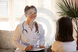 Friendly female doctor pediatrician holding clipboard listening to kid patient