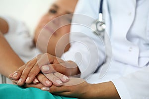 Friendly female doctor's hands holding patient's hand