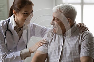 Friendly female doctor support encourage mature grey haired male patient