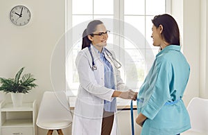 Friendly female gynecologist measuring the round belly of a pregnant woman at the examination room