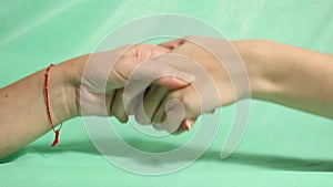 Friendly female handshake with two hands on a turquoise background.