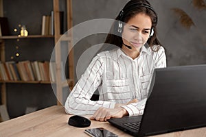 friendly female helpline operator with laptop, call center agent woman with headset using laptop and talking to a client