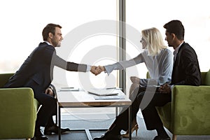 Friendly female and male business partners shaking hands, respect concept