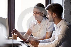 Friendly female mentor training male employee with computer