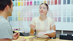 Friendly female seller in a hardware store offers to choose the color of ceramic tiles from the catalog