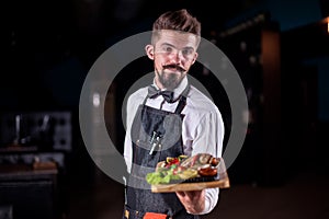 Friendly garcon carries plate with prepared dish in the restaurant.