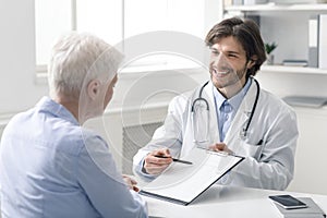 Friendly geriatrician explaining prescription for senior patient photo