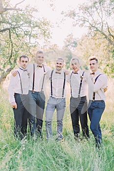 The friendly group photo of the groom and best men in the green summer forest.