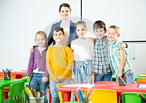 Friendly group of pupils with female teacher in schoolroom