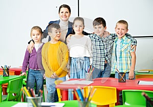 Friendly group of pupils with female teacher in schoolroom