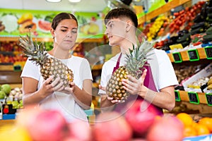 Friendly guy seller helps a girl buyer choose a pineapple