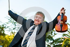 Friendly handicapped boy raising violin outdoors.