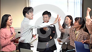 Friendly happy diverse team workers talking laughing together in office. Business team talking laughing at meeting table