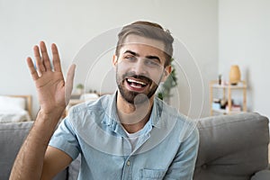 Friendly happy man waving hand saying hello looking at camera