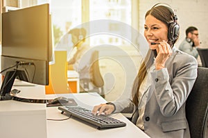 Friendly helpline support operator woman with headphones in call centre