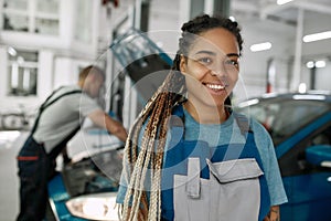 Friendly and Honest Service. Young african american woman, professional female mechanic smiling at camera, while her