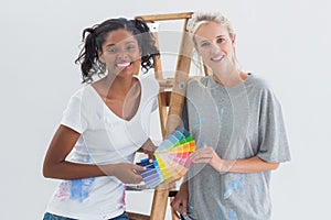 Friendly housemates choosing colour for wall looking at camera