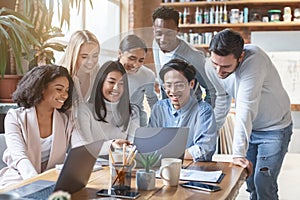 Friendly international business team looking at laptop screen, watching presentation