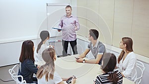 Friendly lawyer sitting with laptop in informal office meeting space, consulting his young female clients