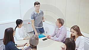 Friendly lawyer sitting with laptop in informal office meeting space, consulting his young female clients