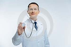 Friendly looking doctor listening to heart with stethoscope