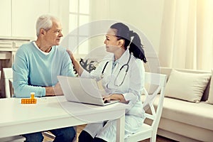 Friendly looking doctor talking to elderly man during consultation