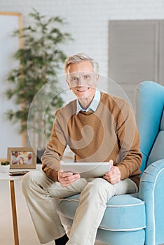 Friendly looking old gentleman working on tablet computer