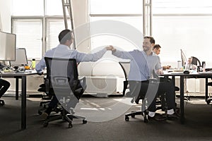 Friendly male buddies fist bumping at work celebrate good teamwo