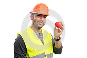 Friendly male constructor in work attire presenting red heart