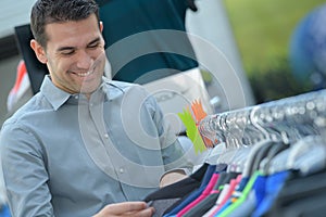 Friendly male customer examining suits in clothes store photo