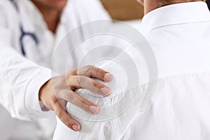 Friendly male doctor hold patient shoulder in office during reception