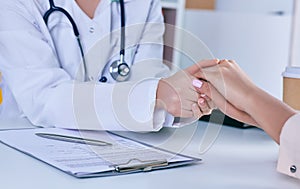 Friendly male doctor reassuring the patient and holding his hands