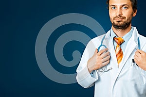 Friendly Male Doctor In White Coat Holds Hand On Stethoscope. People Care Medicine Insurance Concept