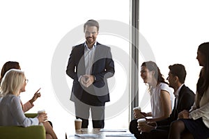 Friendly male leader having fun conversation with office workers team