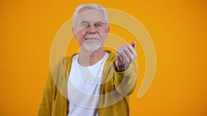 Friendly male pensioner showing come here gesture, welcoming person, invitation