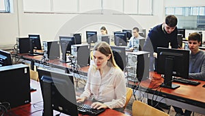 Friendly male teacher lecturing attentive adult students in computer room