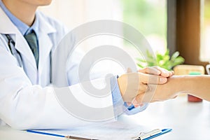 Friendly man doctor`s hands holding male patient`s hand for encouragement and empathy.