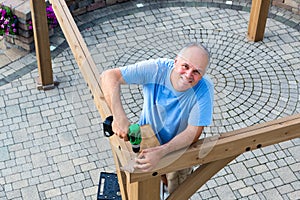 Friendly man erecting a new wooden gazebo