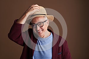 Friendly man smiling while putting on his straw hat