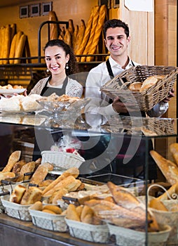 Friendly man and woman selling pastry and loaves