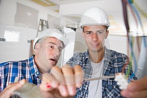 Friendly master electrician and apprentice working on breaker panel