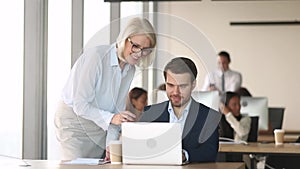 Friendly mature mentor coach executive help employee with computer work