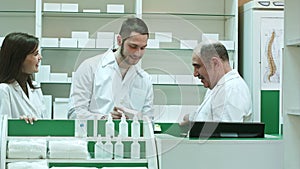 Friendly medical team in lab coat discussing new pills in pharmacy