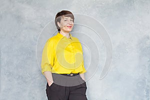 Friendly middle aged business woman in yellow shirt smiling, portrait