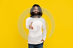 Friendly millennial indian guy outstretching hand and smiling