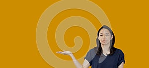 Friendly mixed race casual Asian mature woman presenting gesture with copy space for advertising