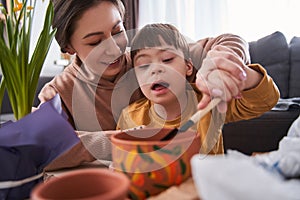 Friendly mother preparing soil for plants while spending time with her son